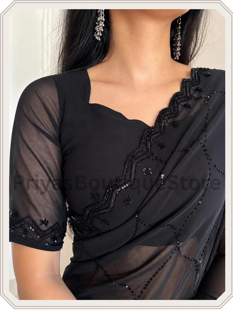 May include: A black saree featuring sheer fabric with intricate black beadwork and sequin embroidery along the borders and across the body. The blouse has short sheer sleeves and a square neckline, with the text PriyasBoutiqueStore visible.