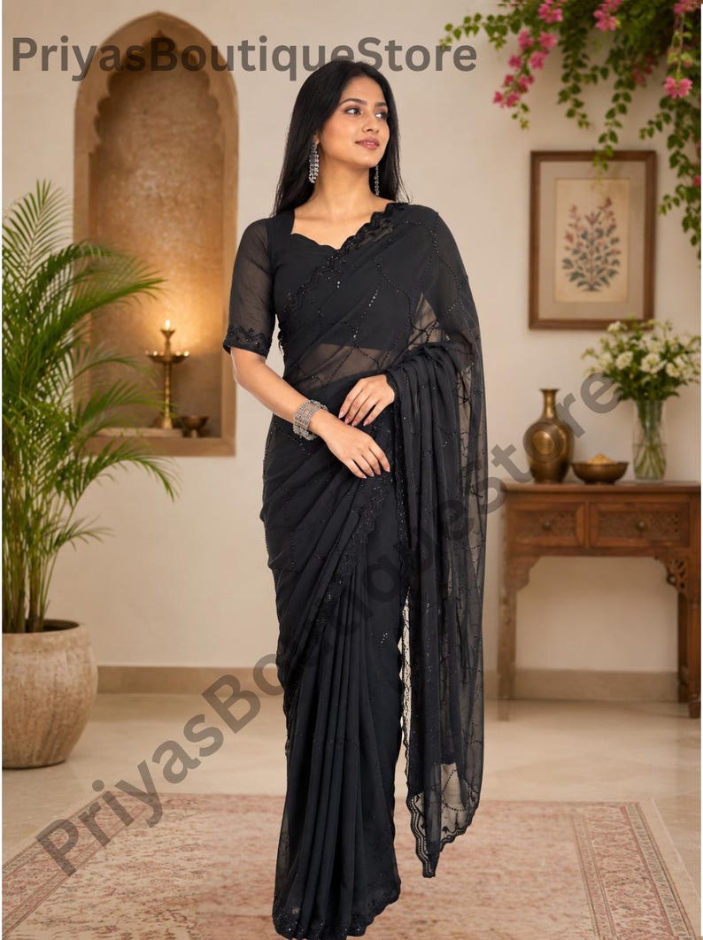 May include: A black saree featuring sheer fabric with intricate tonal embroidery and sequin embellishments. The garment includes a matching blouse with short sleeves and a scalloped neckline, draped elegantly to showcase the detailed border work.