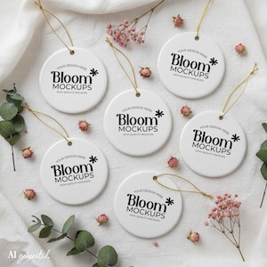 May include: Six white circular ceramic ornaments with gold hanging strings. Each ornament features the black printed text 'YOUR DESIGN HERE Bloom MOCKUPS HIGH-QUALITY MOCKUPS' with a small flower icon. The ornaments are arranged on a white fabric.