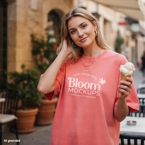 Può includere: Una t-shirt a maniche corte color corallo con la scritta bianca YOUR DESIGN HERE Bloom MOCKUPS HIGH-QUALITY MOCKUPS e una piccola icona a forma di fiore. La maglietta presenta un girocollo e una vestibilità ampia, indossata con orecchini a cerchio.
