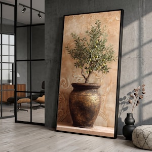 May include: A framed canvas print featuring an olive tree in a decorative pot. The artwork has a warm color palette with a textured background and a black frame. The olive tree has green leaves and small green olives.