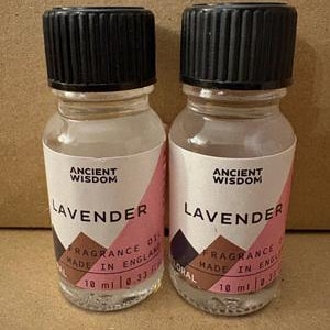 May include: Two clear glass bottles with black ribbed screw caps, each containing 10 ml of lavender fragrance oil. The white labels feature the text Ancient Wisdom, Lavender, Fragrance Oil, and Made in England printed in a clear black font.