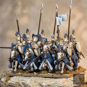 May include: A group of miniature cavalry figures mounted on horses, featuring riders in cream-colored armor with blue accents, tall helmets with blue crests, and long spears. The horses wear blue barding and cream-colored blankets, with one rider holding a white flag.