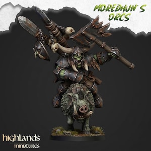 Puede incluir: Una figura en miniatura pintada de un guerrero orco de piel verde con armadura con cuernos montado en un jabalí. El orco sostiene un hacha grande y un arma de asta decorada con calaveras. El texto MOREDHUN'S ORCS y HIGHLANDS MINIATURES es visible.