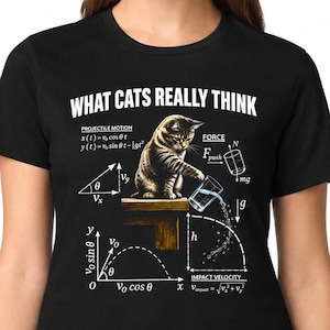 May include: A black t-shirt featuring a graphic of a cat pushing a glass of water off a ledge. The design includes physics equations, projectile motion diagrams, and the text "WHAT CATS REALLY THINK" in white capital letters above the illustration.
