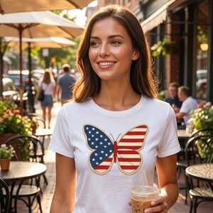 Könnte beinhalten: Weißes T-Shirt mit einem Schmetterlingsdesign im Stil der amerikanischen Flagge. Der Schmetterling hat blaue Flügel mit weißen Sternen und rot-weiß gestreiften Flügeln. Die Person trägt eine blaue Jeans und hält ein Getränk.