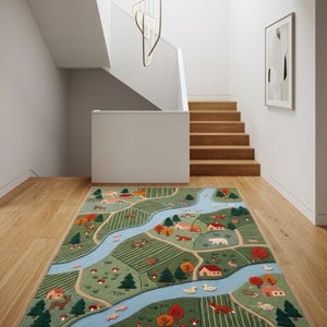 May include: A rectangular area rug featuring a detailed landscape design with a winding light blue river, green fields, small houses with red roofs, various trees, and illustrations of animals including foxes, deer, and ducks in a multi-colored pattern.