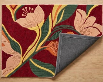 May include: A rectangular area rug featuring a deep red background with large, light peach-colored floral motifs, yellow accents, and dark green leaves. The rug has a textured surface with a corner folded over to reveal a solid dark gray backing.