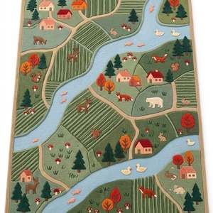 May include: A rectangular area rug featuring a detailed landscape map design with a winding light blue river, green fields, forests of pine trees, small houses with red and orange roofs, and various animals including deer, foxes, and ducks.