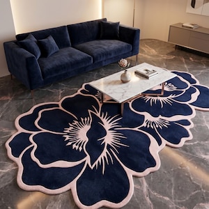 May include: A large, irregularly shaped area rug featuring a dark navy blue floral pattern with light pink outlines. The rug has a soft, textured surface and is designed in the shape of a large, stylized flower with multiple rounded petals.