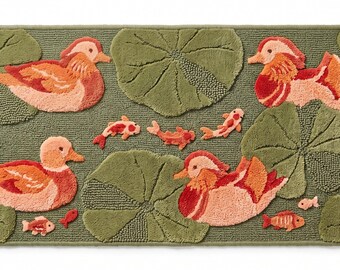 May include: A rectangular bath mat in olive green featuring a tufted design of four orange and pink mandarin ducks swimming among large green lily pads, accompanied by small orange and white koi fish and tiny turtles scattered across the surface.