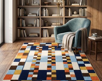 May include: A rectangular area rug featuring a geometric pattern of small squares in shades of navy blue, light blue, orange, yellow, brown, and cream. The design includes a central rectangular panel framed by a border of alternating colored squares.