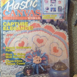 May include: A January 1993 issue of Plastic Canvas World magazine featuring a cover with a Victorian fan craft, a blue tissue cover, and a heart-shaped photo frame. The cover text includes Fun to Stitch, Frame Your Memories, and Capture Elegance.
