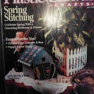 Puede incluir: Portada de la revista "Plastic Canvas Crafts" con el título "Spring Stitching". La imagen presenta una casa para pájaros, una jardinera y texto, incluyendo "Easter Fun for You!" y "Let's Go Fly a Kite! Photo Frame."