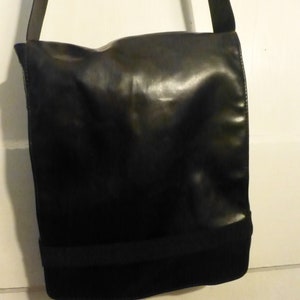 May include: A black leather messenger bag with a black strap. The bag has a flap closure and a single pocket on the front.