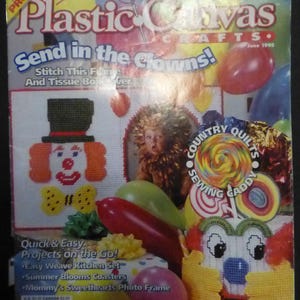 May include: A vintage magazine cover titled "Plastic Canvas Crafts" with the headline "Send in the Clowns!" features colorful stitched clown designs and craft projects. The cover includes text about summer stitching projects and a "Sewing Caddy".