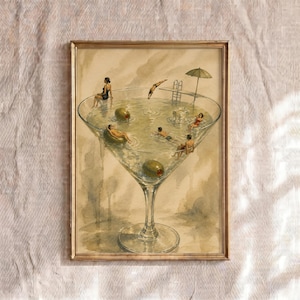 May include: A framed art print featuring a large martini glass filled with liquid, serving as a swimming pool. People are swimming, diving from a board, and relaxing on floats. Two large green olives are submerged in the liquid, and a parasol stands near the edge.