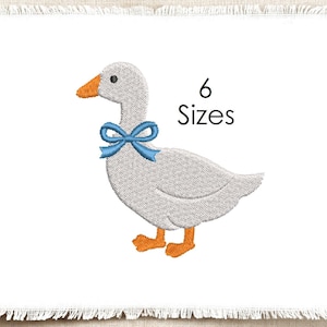 Könnte beinhalten: Ein Stickmuster mit einer hellgrauen Gans mit orangefarbenem Schnabel und Füßen, die eine leuchtend blaue Schleife um den Hals trägt. Das Design ist auf einem weißen Stoffhintergrund mit ausgefransten Rändern zentriert und enthält den schwarzen Text 6 Sizes.
