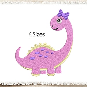 May include: An embroidery design of a pink dinosaur with a long neck, a purple striped bow on its head, and purple spots on its back. The dinosaur has yellow dorsal plates and a yellow underbelly. The text 6 Sizes is printed in black.