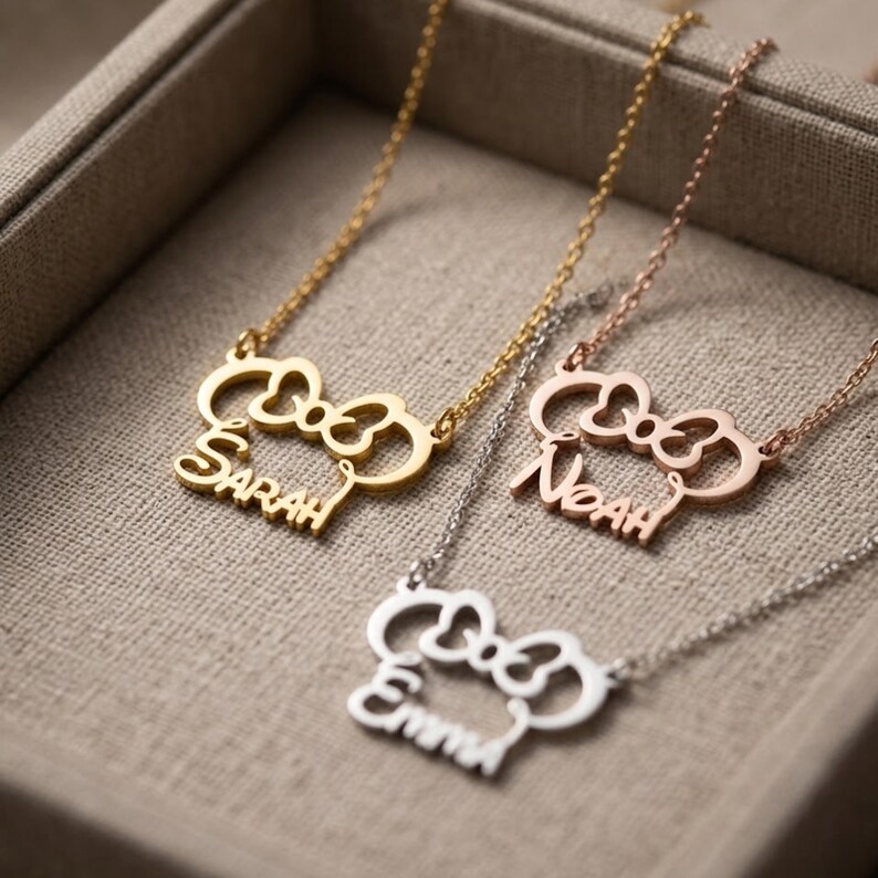 May include: Three personalized necklaces with bow-shaped pendants. One is gold with the name "Sarah", another is rose gold with "Noah", and the third is silver with "Emma". Each necklace has a delicate chain.