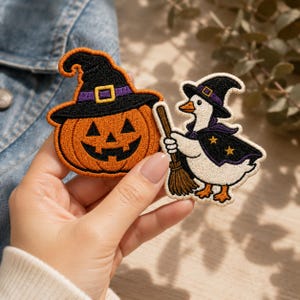 May include: Two embroidered patches featuring Halloween themes. One patch is an orange jack-o'-lantern wearing a black witch hat with a purple band. The second patch is a white goose wearing a black witch hat and cape with gold stars, holding a broom.