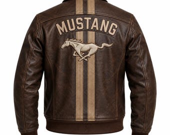 May include: A brown leather jacket featuring two vertical beige stripes down the center back. The word MUSTANG is embroidered in beige above a beige horse graphic. The jacket has a classic collar, long sleeves, and a ribbed brown hem and cuffs.