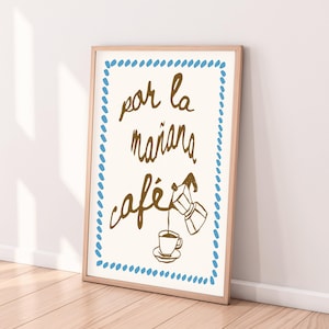 Może przedstawiać: Oprawiony wydruk artystyczny na jasnokremowym tle z niebieską przerywaną ramką. Napis "por la mañana café" wykonano brązową kursywą, a obok znajduje się brązowy rysunek kawiarki przelewającej kawę do filiżanki.