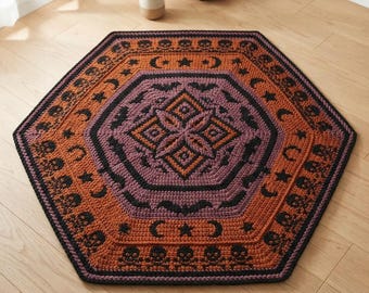 May include: A hexagonal crochet rug featuring a central geometric star pattern in purple and orange, surrounded by concentric bands of black bats, crescent moons, stars, and skulls on an orange background, all bordered by a thick black edge.