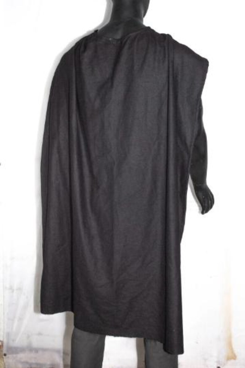 May include: A solid black cloak featuring a simple, unadorned design that drapes over the shoulders and extends down the back. The garment is made of a dark, opaque fabric with a matte texture, covering the upper body and hanging loosely to the waist.