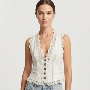 May include: A white sleeveless vest featuring a deep V-neckline adorned with intricate cream-colored lace trim. The garment includes a front button closure with five buttons, vertical seam detailing, and a scalloped lace hemline at the waist.