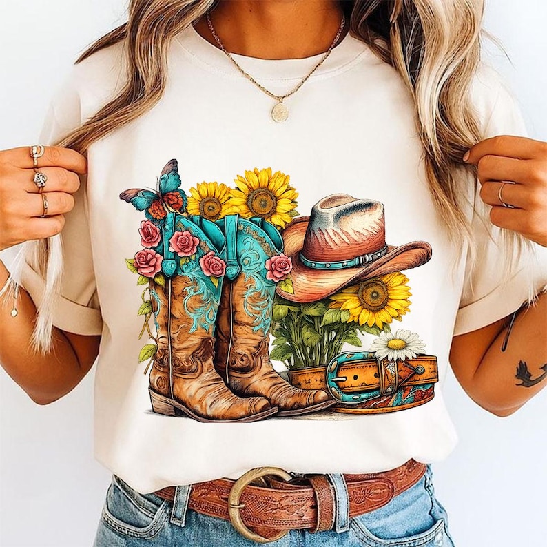 Pu&ograve; includere: Una t-shirt color crema con una stampa grafica di due stivali da cowboy marroni con accenti turchesi, rose rosa, una farfalla blu, un cappello da cowboy marrone, girasoli gialli e una cintura in pelle marrone con fibbia argentata.