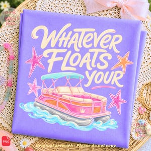 May include: A light purple t-shirt featuring a graphic of a pink pontoon boat on blue water, surrounded by four pink and orange stars. The text "WHATEVER FLOATS YOUR" is printed in a large, cream-colored, stylized script font above the boat.