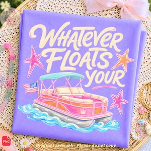 May include: A lavender t-shirt featuring a graphic of a pink pontoon boat on blue water with the text "WHATEVER FLOATS YOUR" in cream-coloured lettering. The design includes a small American flag on the boat and three pink and orange stars.