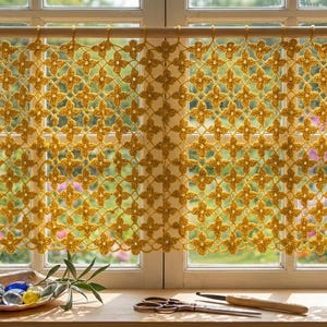 May include: A mustard yellow crochet curtain featuring a repeating floral motif pattern, suspended from a wooden rod. The curtain is crafted with an openwork design, allowing light to pass through the intricate, interconnected flower shapes.