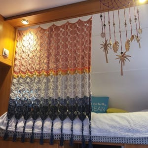 Può includere: Un arazzo rettangolare all'uncinetto con un motivo a colori sfumati che passa dal rosa polvere al giallo, bianco e grigio scuro. Il pezzo presenta un design in pizzo a forma di foglia, un bordo superiore smerlato e nappe grigio scuro.