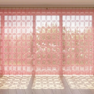 May include: A set of floor-length, semi-sheer curtains in a soft pink hue, featuring a repeating geometric lace pattern. The curtains are hung from a simple metal rod, allowing light to filter through and cast intricate shadows on the floor.