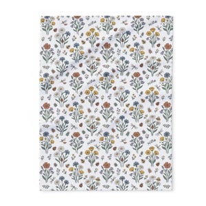 May include: A white fabric featuring a repeating pattern of botanical illustrations including orange, yellow, and blue flowers with green stems. The design is interspersed with small insects such as ladybirds, bees, and dragonflies throughout the print.