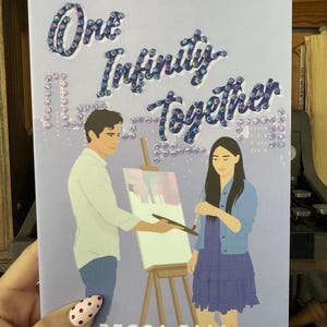 May include: The book cover for "One Infinity Together" by Becca Fall, from "The Burrow Series." The image shows a man painting on a canvas, with a woman looking on. The title is in a sparkly font, with the author's name below.