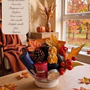 May include: A clear bowl filled with a collection of items including a blue Nivea deodorant spray, a red candle, a squirrel figurine, a pinecone, a tealight candle, artificial autumn leaves, red berries, and various packaged snacks.