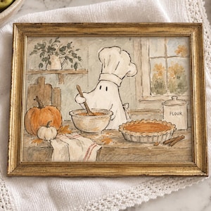 Può includere: Un'illustrazione incorniciata ad acquerello raffigurante un fantasma con un cappello da chef che mescola in una ciotola in cucina. La scena include una zucca, una torta, un barattolo di farina con scritto FLOUR e una finestra. La cornice è dorata.