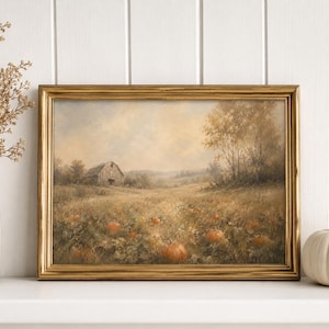 May include: A framed landscape painting depicting a rural field with scattered orange pumpkins and a barn in the distance. The artwork is displayed in a gold-toned frame, positioned between a white vase with dried branches and a white pumpkin.