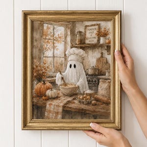 May include: A framed wall art print featuring a ghost wearing a chef hat and mixing ingredients in a bowl. The kitchen scene includes pumpkins, a bag labeled FLOUR, and a sign reading PUMPKIN SPICE & EVERYTHING NICE. The artwork has warm autumn tones.