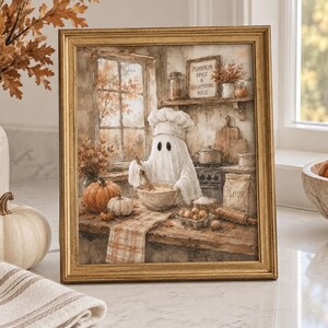 May include: A framed wall art print featuring a ghost wearing a chef hat and mixing ingredients in a bowl. The kitchen scene includes pumpkins, a bag of flour, and a sign that reads PUMPKIN SPICE & EVERYTHING NICE in a warm, autumnal color palette.