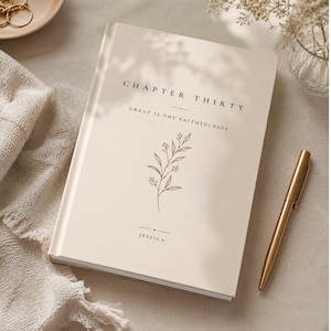 Op de afbeelding: Een beige notitieboek met harde kaft waarop de tekst "CHAPTER THIRTY" en "GREAT IS THY FAITHFULNESS" in het zwart is gedrukt. Een lijntekening van een takje staat in het midden van de kaft, met de naam "JESSICA" onderaan gedrukt.