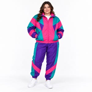 May include: A matching tracksuit set featuring a zip-up jacket and pants in a vibrant color-blocked pattern of bright pink, teal, and purple. The jacket has a high collar and long sleeves, while the pants have a relaxed fit with elastic cuffs.