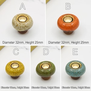 May include: Five round ceramic cabinet knobs labeled A through E, each featuring a glossy speckled glaze in beige, orange, yellow, green, or blue with a central gold-tone metal disc. Each knob has a diameter of 32mm and a height of 25mm.