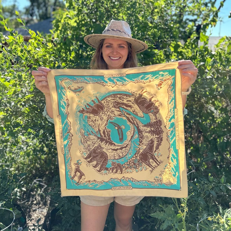 Peut inclure: Un bandana jaune avec une bordure turquoise pr&eacute;sente une illustration color&eacute;e d'animaux et de plantes. Le bandana porte l'inscription "ROCKARTWORKS" et "GROW THE THINGS YOU LOVE".