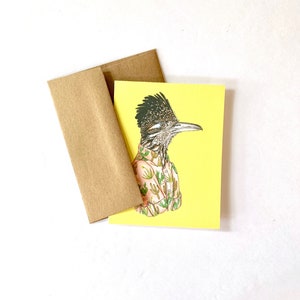 May include: A yellow card with a cartoon illustration of a roadrunner wearing a pink shirt with a cactus pattern. The roadrunner is looking to the right.