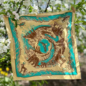 Peut inclure: Un bandana jaune avec une bordure turquoise repr&eacute;sentant un motif d'animaux et de plantes du parc national de Grand Teton. Le bandana porte l'inscription "RKARTWORK" et "GRAND TETON NATIONAL PARK".