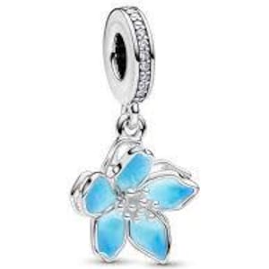 May include: A silver charm with a dangling blue flower design. The flower has five petals with a light blue enamel finish. The charm's top loop is adorned with small, clear stones.